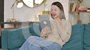 Video Chat on Tablet by Young Woman on Sofa