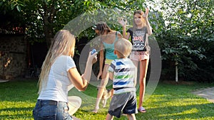 video of cheerful laughing children catching soap bubbles that mother is blowing in park