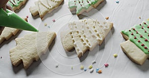 Video of christma cookies being decorated with green sugar icing with copy space on white background