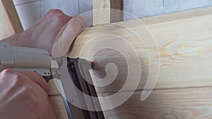 Video close up cropped man hands using pneumatic stapler, nailer, nail gun for wooden timber board. Wooden framework