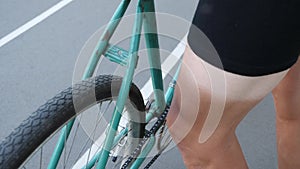 This video is about Close up view of a green track fixed retro bicycle on a velodrome and a cyclist leg with sun tun