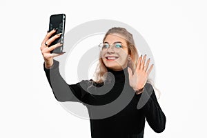 Video communication via smartphone. A young woman is using phone for video call. She talks with her friends