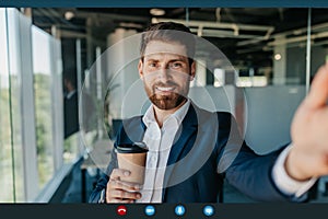 Video conference. Positive businessman making virtual call and drinking coffee, smiling at camera, pov screenshot