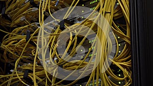 Video contains noise. Yellow Fiber Optical Cables close up on Datacenter. Telecommunication Broadband. Blink Green Led