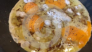 Video of cooking of fried eggs from several eggs with onions and black pepper, liquid egg white, a teflon frying pan