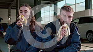 Video with a couple working at a car wash who just took a short break to eat a banana.