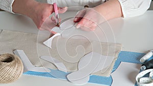 Video cropped female seamstress, designer hands cutting with scissors paper patterns as templates for sewing on table