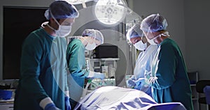 Video of diverse group of surgeons operating on patient in operating theatre