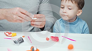 Video of father and little boy making animals from plasticine