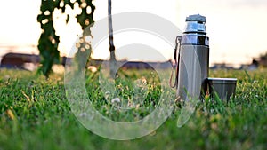 Video footage of a thermos in the evening sun on a background of a landscape