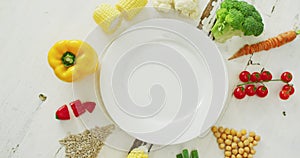 Video of fresh vegetables arranged around white plate with copy space on white rustic background