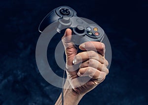 Video game console controller in gamer hand against the background of the dark wall