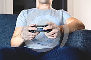 Video game controller in hand for console gaming. Gamer guy playing tv videogame with control gamepad or joystick while sitting. photo