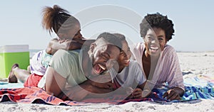 Video of happy african american family lying on beach and laughing