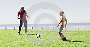 Video of happy african american father and son playing soccer outdoors and having fun