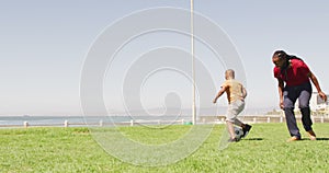 Video of happy african american father and son playing soccer outdoors and having fun