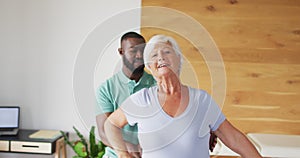 Video of happy african american male physiotherapist examining caucasian senior woman