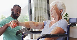 Video of happy african american male physiotherapist exercising with caucasian senior woman