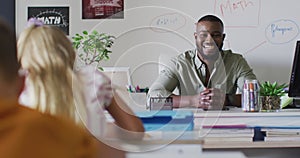 Video of happy african american male teacher sitting at desk during math lesson