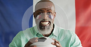 Video of happy african american man with flag of france holding soccer ball
