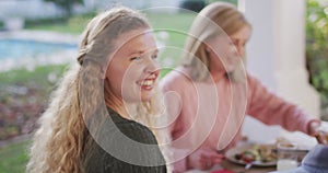 Video of happy caucasian mother and grandmother laughing at outdoor family dinner table