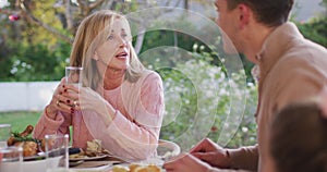 Video of happy caucasian senior mother and adult son talking at outdoor family dinner table