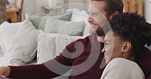 Video of happy diverse couple watching tv on sofa