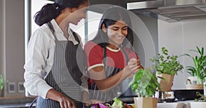 Video of happy diverse female friends cutting vegetables and preparing meal