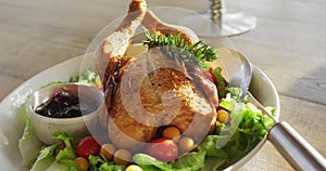Video of healthy appetising meal with roast chicken, sauce and salad on wooden dinner table