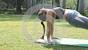 Video of an Indian fit woman doing the reverse plank pose exercise in park.