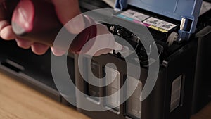 Video instruction, technology, media, office, stationery concept - close-up of male hands preparing new inkjet printer