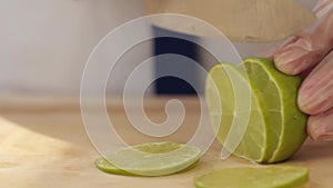 Video from the kitchen of the restaurant. The cook cuts the green lime with a big knife. Moving camera.