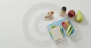 Video of lunch box with sandwich and healthy vegetable snacks with nuts and fruit and copy space