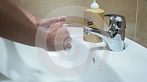 Video of mature woman washing her hands with liquid soap under the water tap in the bathroom. Hygiene concept hand deta