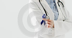 Video of midsection of caucasian female doctor holding blue colon cancer ribbon, with copy space