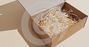 Video of opened cardboard box with paper shavings and copy space over brown background