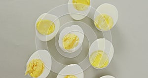 Video of overhead view of halves of hard boiled eggs on grey background