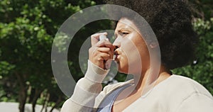 Video of plus size african american woman using inhalator outdoors