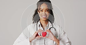 Video of portrait of smiling biracial female doctor holding heart on white background