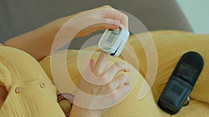 In this video, a pregnant woman is seen measuring her oxygen levels using a pulse oximeter. The slow motion footage