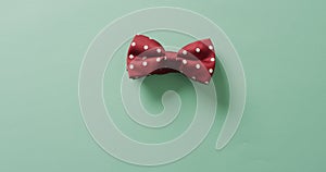 Video of red dotted bow tie lying on green background