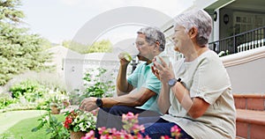 Video of relaxed biracial senior couple drinking coffee in garden