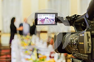 Video shooting at a restaurant at a Banquet. Camcorder with LCD display. People in the hall