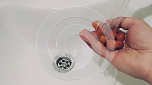 Video on a smartphone, as a man in a white sink washes strawberries