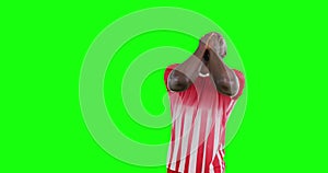 Video of smiling african american male soccer player cheering on green screen background