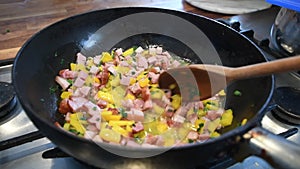 Video stirring in a frying pan with chopped ham, onion and pepper