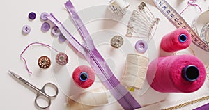 Video of tape measure, scissors, safety pins, reels of thread and zips on white background