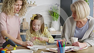 Video of three generations of women making handmade Easter decorations.