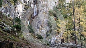 Video of a trail on a rocky mountain with a waterfall.