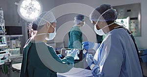 Video of two diverse female surgeons discussing x-ray on tablet in operating theatre